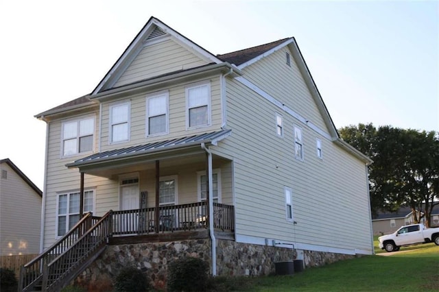 view of front of house featuring cooling unit, a porch, and a front yard