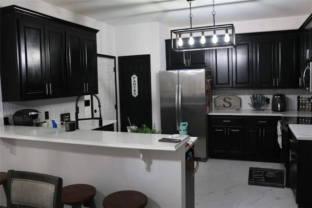 kitchen with pendant lighting, a breakfast bar area, appliances with stainless steel finishes, tasteful backsplash, and kitchen peninsula