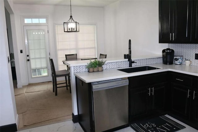 kitchen featuring dishwasher, sink, decorative backsplash, hanging light fixtures, and kitchen peninsula