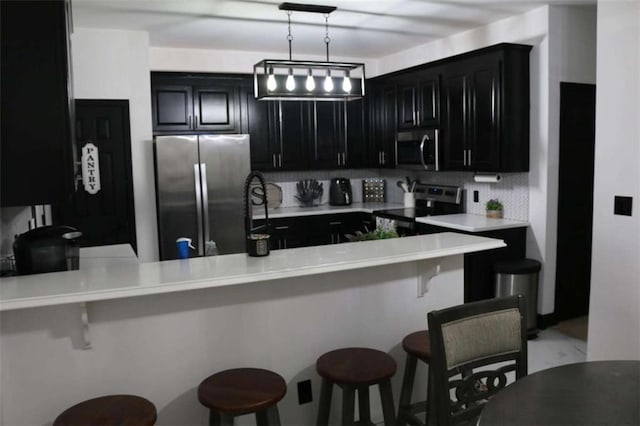 kitchen with decorative backsplash, stainless steel appliances, kitchen peninsula, and a breakfast bar area