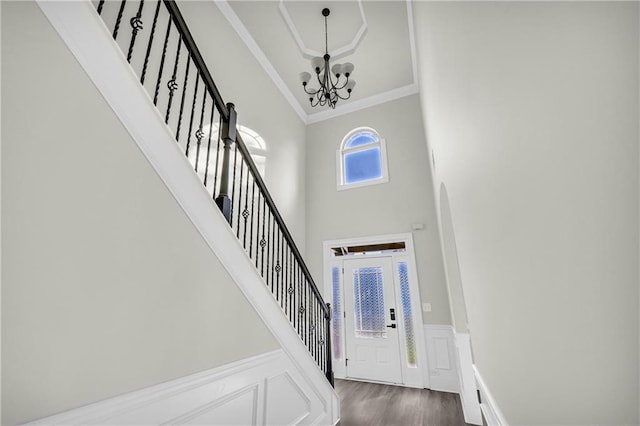 foyer entrance with dark hardwood / wood-style flooring, a high ceiling, a chandelier, and ornamental molding