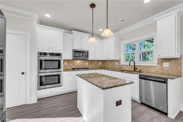 kitchen featuring a center island, white cabinetry, stainless steel appliances, decorative light fixtures, and sink