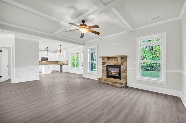 unfurnished living room with a stone fireplace, coffered ceiling, ceiling fan, and dark hardwood / wood-style flooring