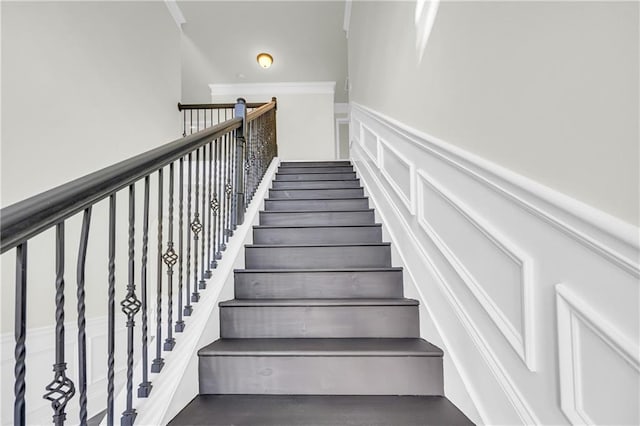 stairs featuring a towering ceiling, hardwood / wood-style flooring, and crown molding