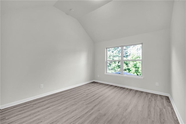 spare room featuring lofted ceiling and light hardwood / wood-style flooring