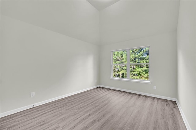 unfurnished room with light hardwood / wood-style floors and vaulted ceiling