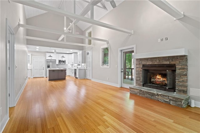 532 Coffee Cove Dr, Jasper, GA 30143 - unfurnished living room with high vaulted ceiling, a stone fireplace, baseboards, light wood-type flooring, and a sink