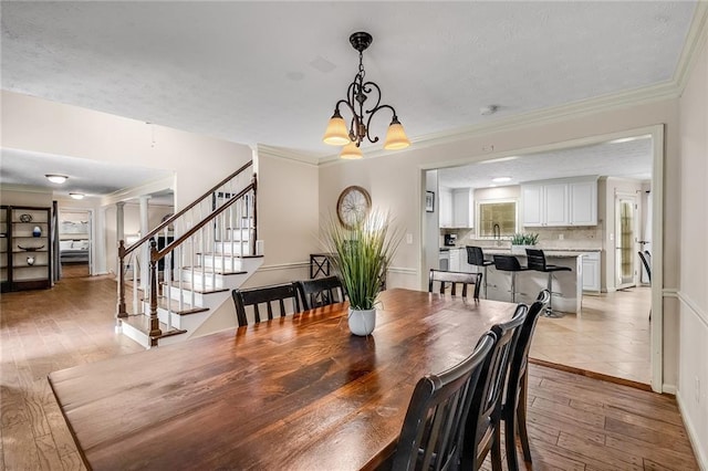 dining room featuring crown molding, light hardwood / wood-style flooring, sink, and a chandelier