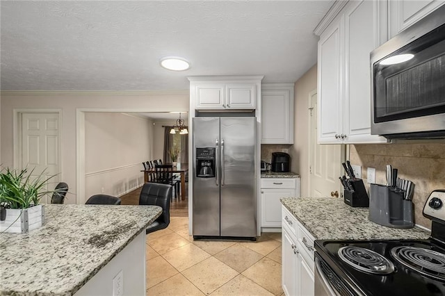 kitchen with crown molding, light stone countertops, stainless steel appliances, white cabinetry, and light tile patterned flooring