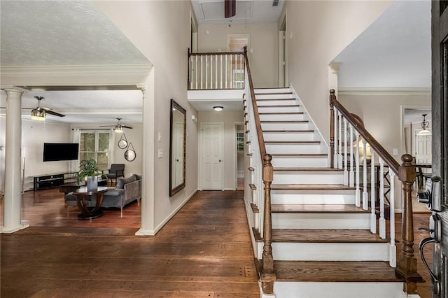 stairs featuring crown molding, a textured ceiling, decorative columns, ceiling fan, and hardwood / wood-style flooring