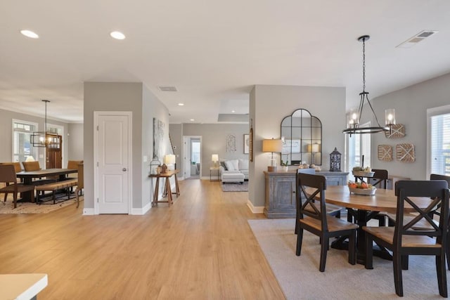dining area with visible vents, light wood-type flooring, a notable chandelier, and a healthy amount of sunlight