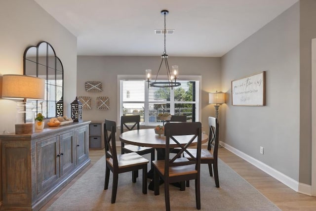 dining area featuring visible vents, baseboards, light wood finished floors, and an inviting chandelier