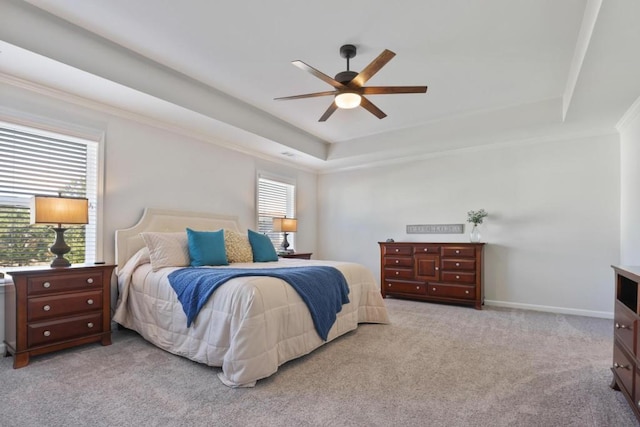 bedroom featuring baseboards, light carpet, a ceiling fan, crown molding, and a tray ceiling