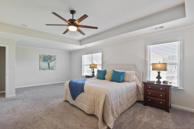 carpeted bedroom featuring visible vents, baseboards, multiple windows, and a tray ceiling