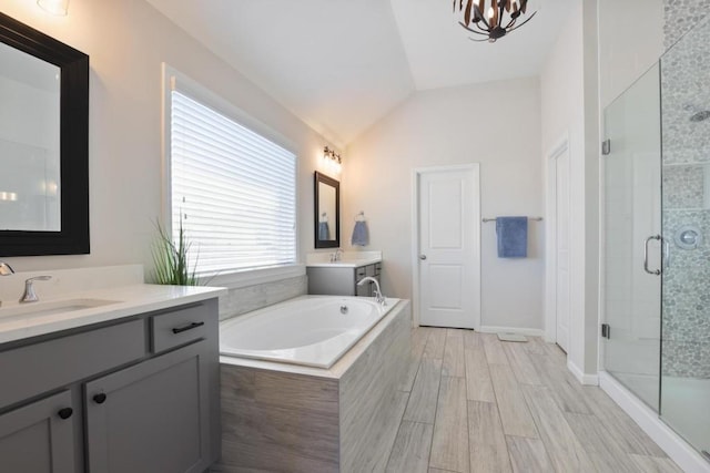 full bath with two vanities, a stall shower, a bath, lofted ceiling, and a sink