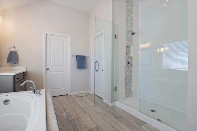 bathroom with vanity, baseboards, a shower stall, a bath, and wood finished floors
