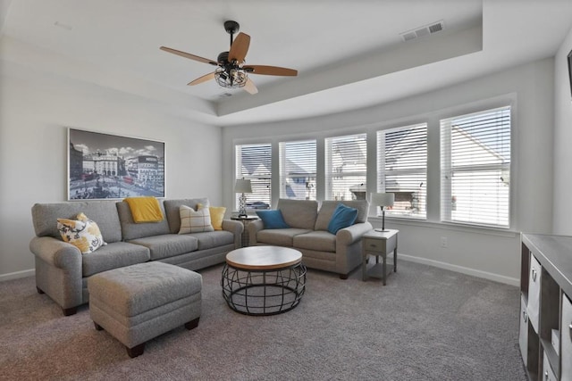 living area with a tray ceiling, baseboards, carpet, and a wealth of natural light