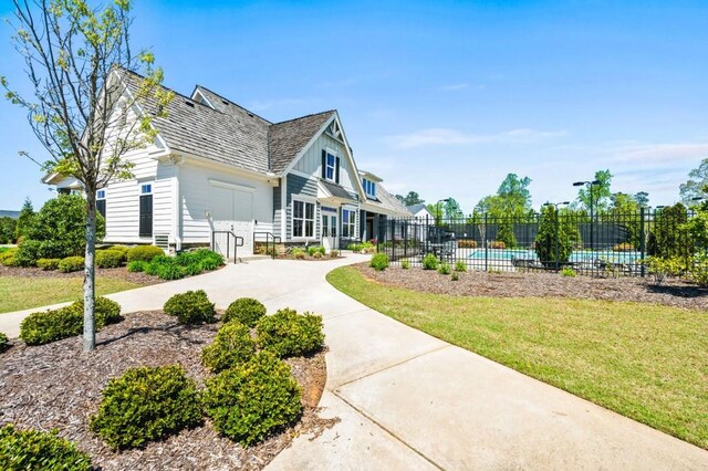surrounding community with a pool, fence, and a lawn