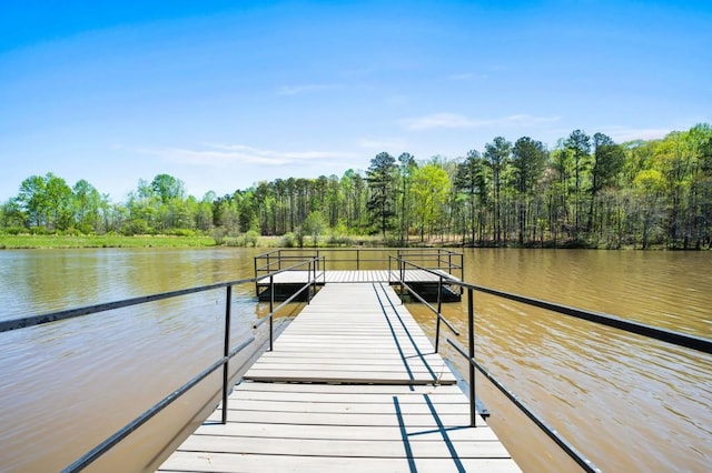 view of dock with a forest view and a water view