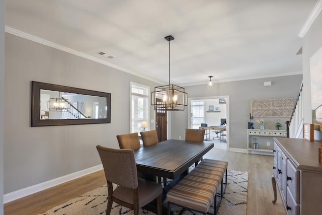dining room featuring visible vents, baseboards, a chandelier, crown molding, and light wood-style flooring