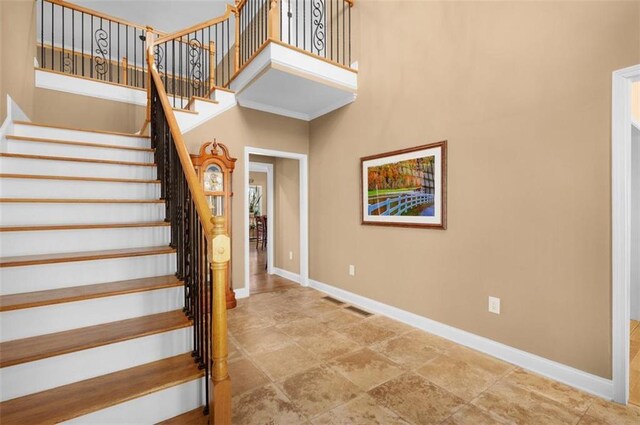 stairs with baseboards and a high ceiling