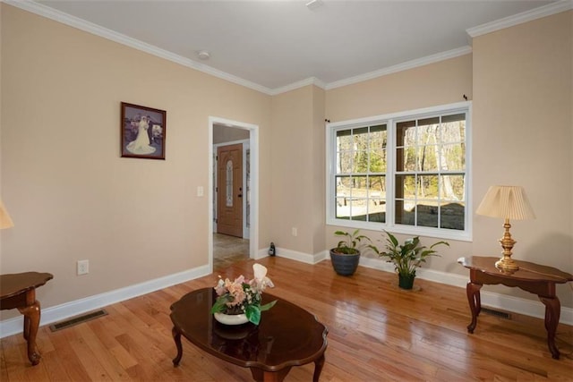 sitting room featuring visible vents, wood-type flooring, baseboards, and ornamental molding