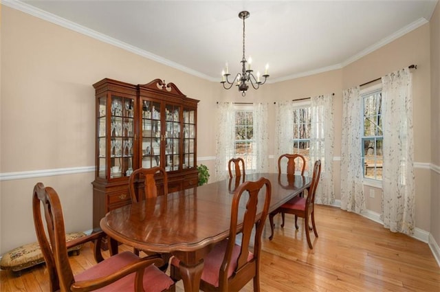 dining space featuring crown molding, baseboards, light wood finished floors, and a chandelier