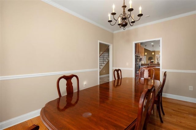 dining space featuring wood finished floors, baseboards, stairs, crown molding, and a chandelier