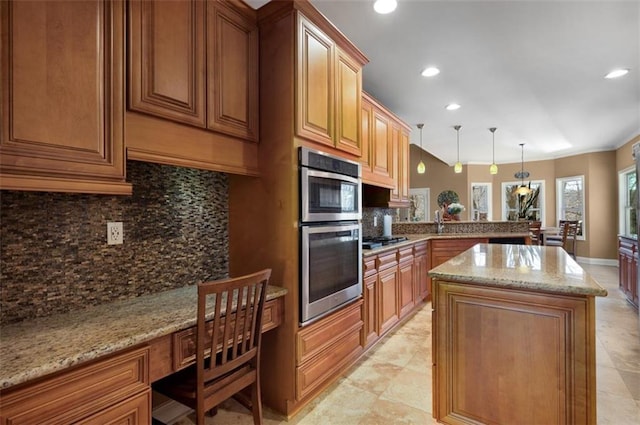 kitchen featuring light stone countertops, a kitchen island, a peninsula, decorative backsplash, and built in desk