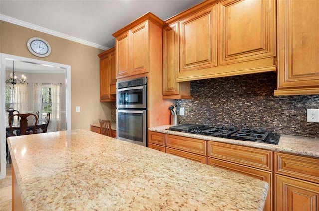 kitchen featuring backsplash, crown molding, black gas cooktop, an inviting chandelier, and stainless steel double oven