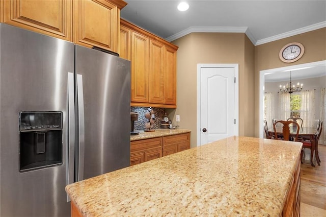 kitchen featuring a center island, light stone countertops, ornamental molding, an inviting chandelier, and stainless steel refrigerator with ice dispenser