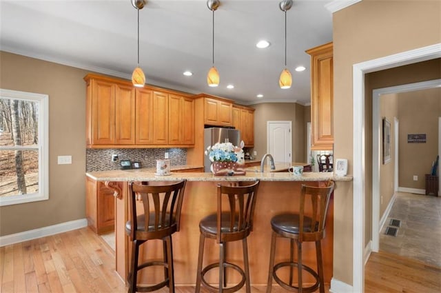 kitchen with light wood-type flooring, visible vents, freestanding refrigerator, crown molding, and decorative backsplash