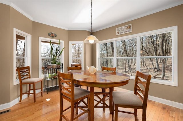 dining room with light wood-style flooring, baseboards, visible vents, and ornamental molding