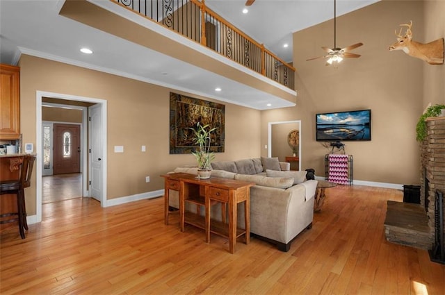 living room with a high ceiling, baseboards, light wood-type flooring, and ceiling fan