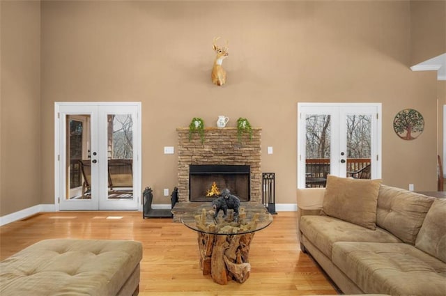 living room with french doors, wood finished floors, baseboards, and a towering ceiling