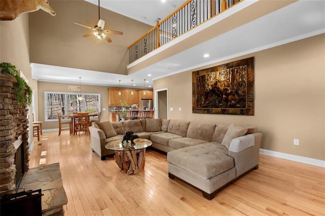 living room featuring a ceiling fan, crown molding, baseboards, and light wood-type flooring