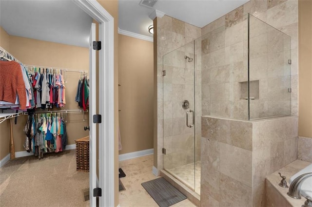 full bath with a walk in closet, crown molding, baseboards, and a stall shower