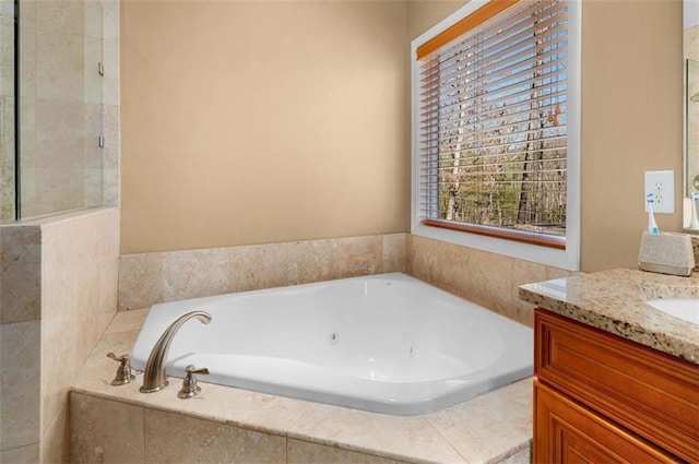 bathroom featuring a tub with jets, vanity, and tiled shower