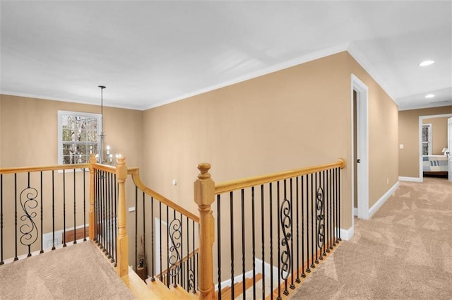 hallway with an upstairs landing, ornamental molding, carpet, baseboards, and a chandelier