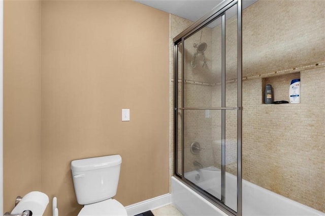 bathroom with combined bath / shower with glass door, baseboards, and toilet