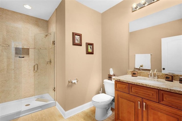 full bath featuring baseboards, toilet, vanity, and a shower stall