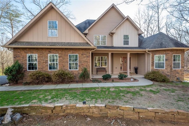 view of front of home with board and batten siding, stone siding, and roof with shingles