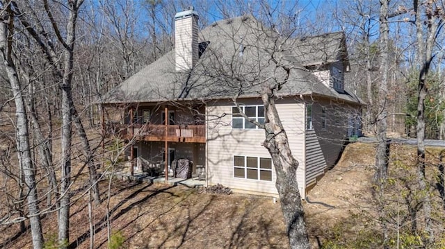 rear view of house with a wooden deck, a patio, and a chimney