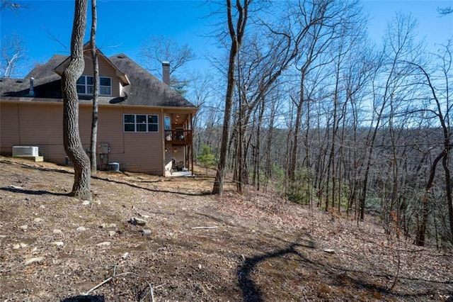 exterior space featuring a wooded view and a chimney