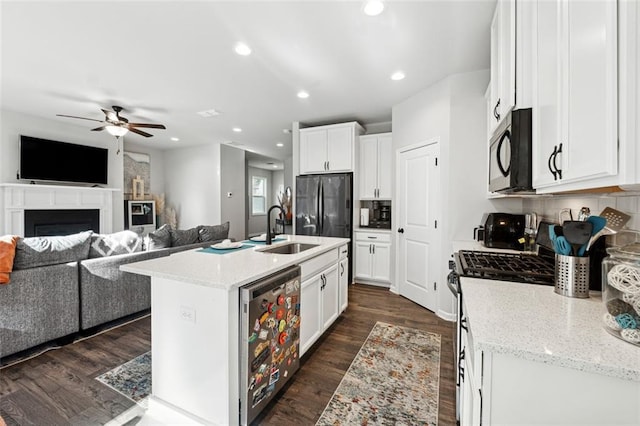 kitchen featuring a kitchen island with sink, dark wood-type flooring, sink, appliances with stainless steel finishes, and beverage cooler