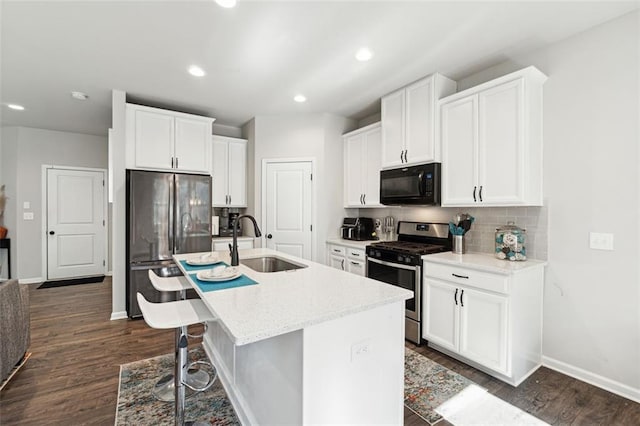 kitchen with dark wood-type flooring, a center island with sink, stainless steel appliances, and sink