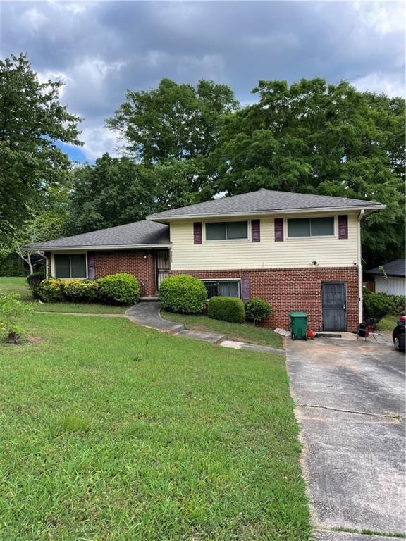 split level home with a front yard, brick siding, and driveway