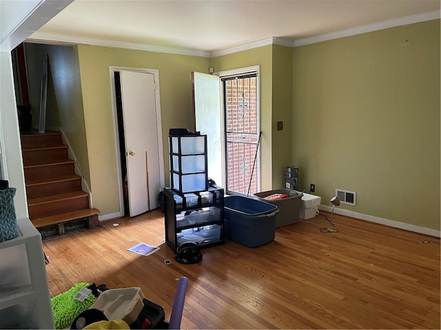 miscellaneous room featuring visible vents, wood finished floors, ornamental molding, and stairs