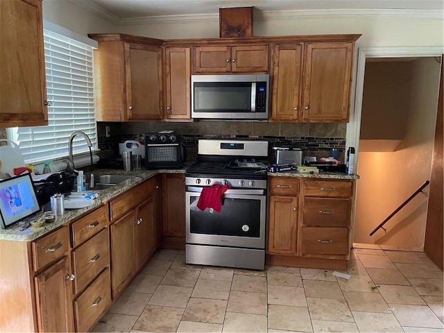 kitchen featuring stainless steel appliances, brown cabinets, tasteful backsplash, and a sink