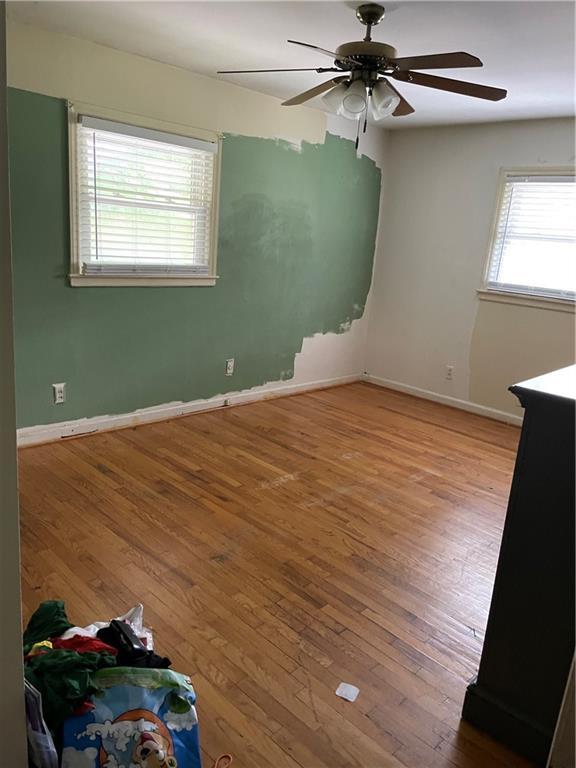 unfurnished room with hardwood / wood-style flooring, baseboards, and a ceiling fan